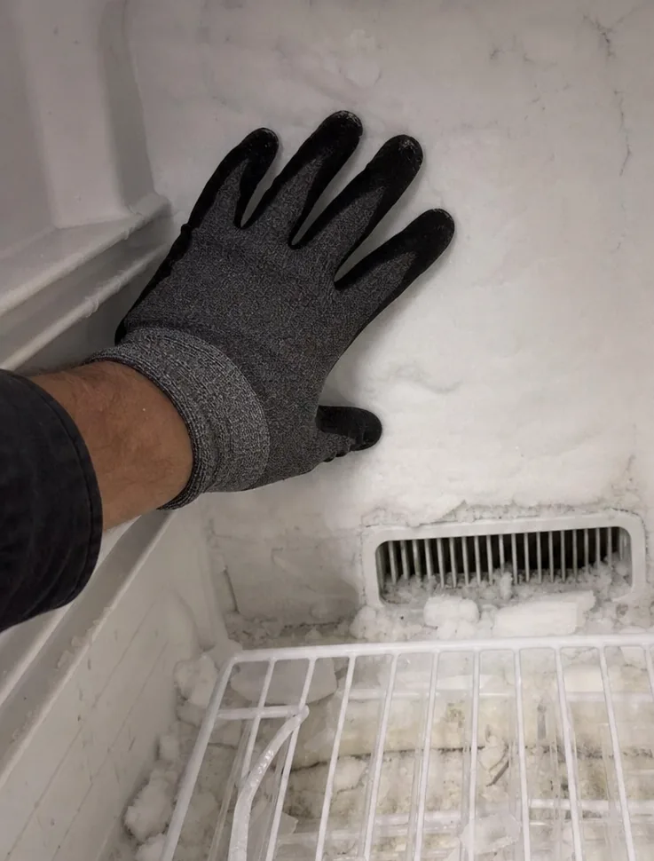 Frost built up heaviest along the upper corner of a freezer liner, thinning as it runs down the wall.